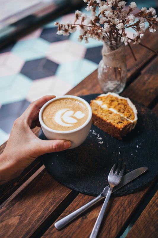 En kopp kaffe med latte art och ett kaffebröd på ett träbord