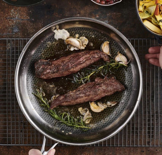 Stekpanna miljöbild med kött och örter