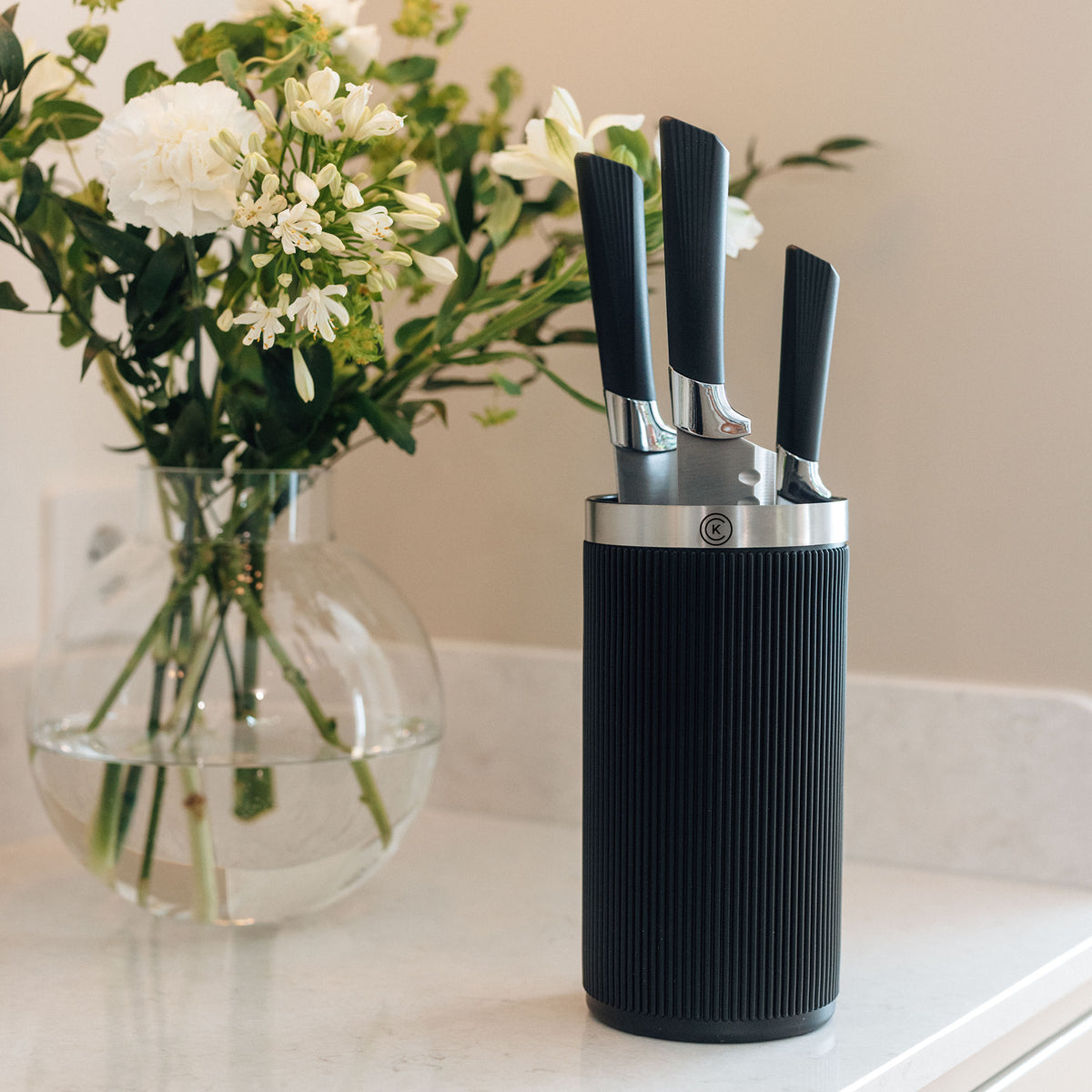 Svart Master Core knivställ från Catarina König med knivar på en köksbänk bredvid en blomvas