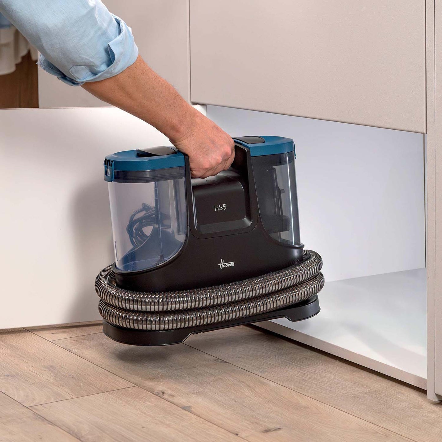Hand lyfter Hoover HS5 i handtaget – kompakt och lätt att bära och förvara