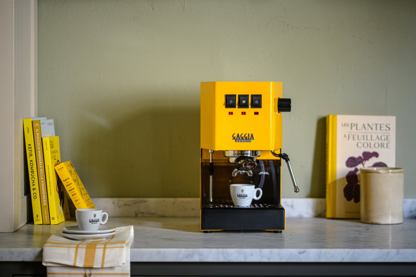 Miljöbld Gaggia Classic E24 espressomaskin gul på bänk med espressokopp, och böcker