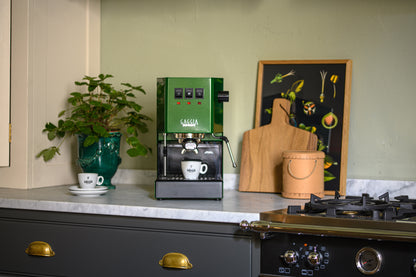 Miljöbild Gaggia Classic E24 espressomaskin grön på köksbänk med kopp serveringsbricka och en grön växt