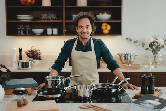 Markus Aujalay står bakom en köksbänk med häll och många av sina produkter framför sig.