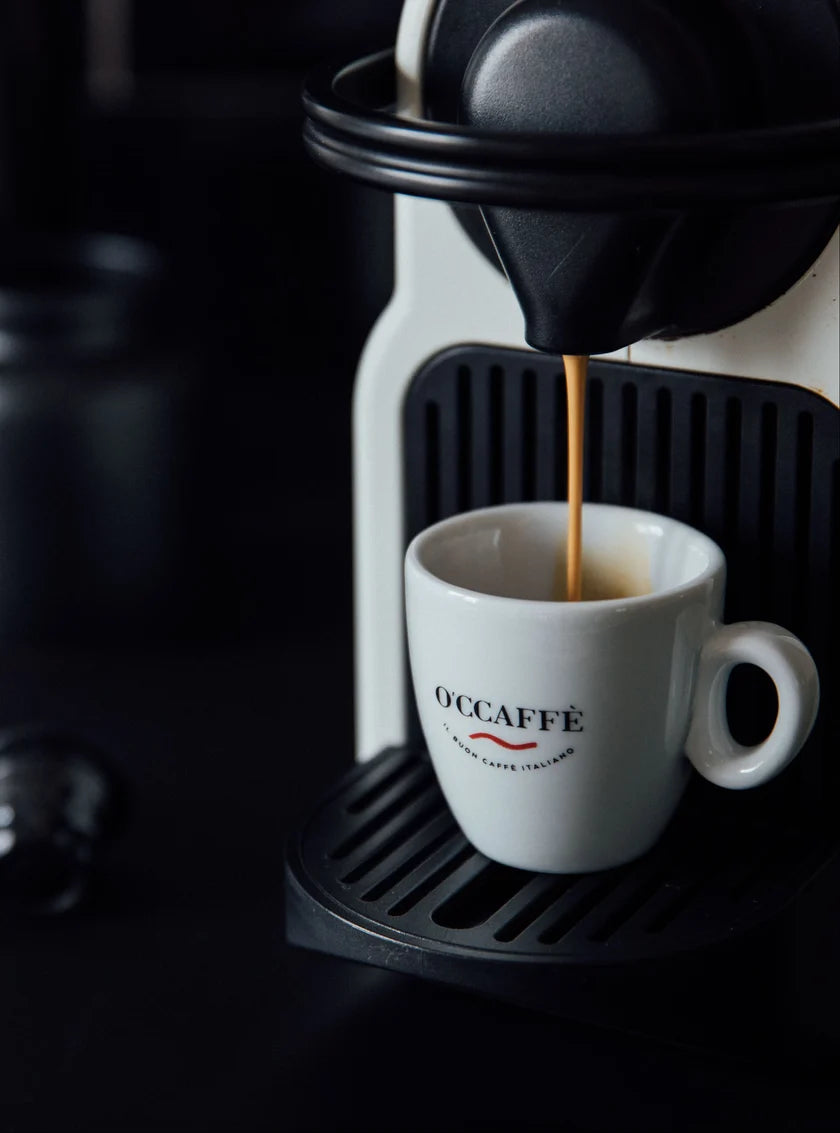 Espresso bryggs från en kapselmaskin ner i en vit O'Ccaffè-kopp